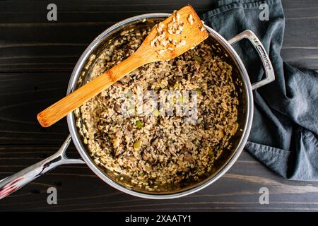 Pilz-Risotto in einer großen Sautepfanne mit Holzspachtel: Frisch gekochtes Risotto in einer Edelstahl-Sautepfanne mit Bambusspachtel Stockfoto