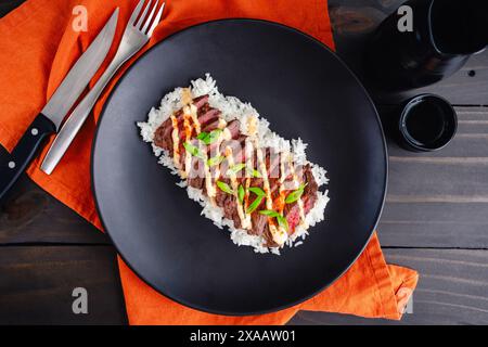 Koreanisches Rock Steak mit Kimchi Aioli über Jasminreis: Gegrilltes Rock Steak in Scheiben geschnitten und garniert mit Aioli, Gochugaru, Zwiebeln und Sesamsamen Stockfoto