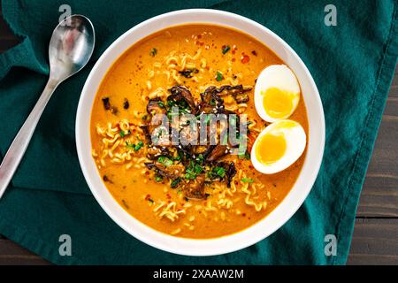 Kokos-Curry-Ramen mit weichem gekochtem Ei und Pilzen: Thai-Ramen-Nudeln in heißer und würziger Brühe mit Shiitake-Pilzen Stockfoto