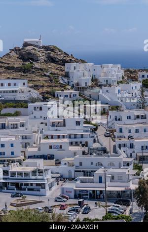 IOS, Griechenland - 4. Mai 2024 : Blick auf verschiedene weiß getünchte Hotels, eine Kirche auf dem Hügel und die Ägäis im Hintergrund in iOS Griechenland Stockfoto