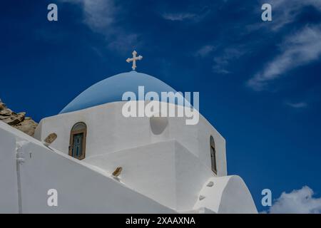 Ein Kreuz auf der Spitze einer orthodoxen, weiß getünchten Kirche in iOS Griechenland und ein blauer Himmel im Hintergrund in iOS Griechenland Stockfoto