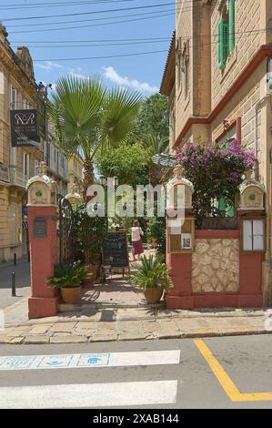 Sitges, Barcelona, Spanien - 5. Juni 2024: Bild des Eingangs zu den Zimmern des Hotels Sitges Royal, unter dem die rosafarbenen Säulen und das tropische Grün hervorgehoben werden Stockfoto