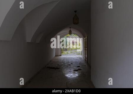 Fotografie eines dunklen Tunnelbogens in einem mittelalterlichen Haus mit offenem Tor am Ende Stockfoto