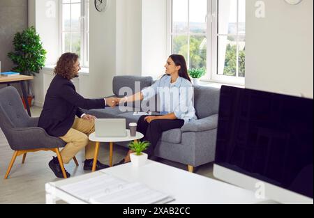 Junge Geschäftsleute, Mann und Frau, die sich im Büro treffen und die Hände schütteln Stockfoto