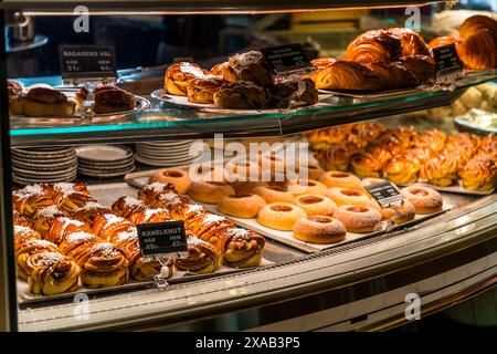 Kanellbullar und anderes Gebäck in einer Bäckerei in Uppsala, Schweden. Diese werden traditionell während eines Fikas in Schweden gegessen. Fika bedeutet, eine Aktivität zu unterbrechen, um mit Familie, Freunden oder Kollegen Kaffee zu trinken. Ein Fika kann zwischen 15 und 45 Minuten dauern. Ein Süßes, fikabröd genannt, wird oft mit dem Kaffee gegessen. Drottninggatan, Uppsala, Schweden Stockfoto