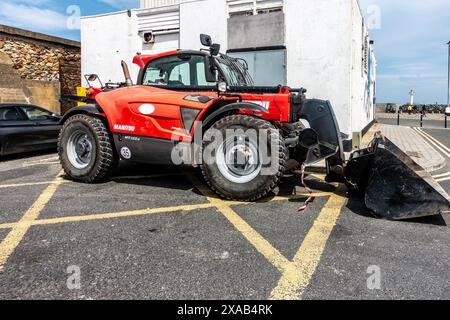 Ein roter Manitou-Telehandler parkte in der Nähe eines Gebäudes am Pier in Howth, Dublin, Irland. Stockfoto