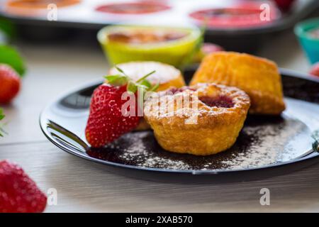 Süße Quark-Muffins mit Erdbeerfüllung, auf einem Teller auf einem Holztisch. Stockfoto