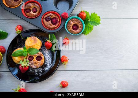 Süße Quark-Muffins mit Erdbeerfüllung, auf einem Teller auf einem Holztisch. Stockfoto