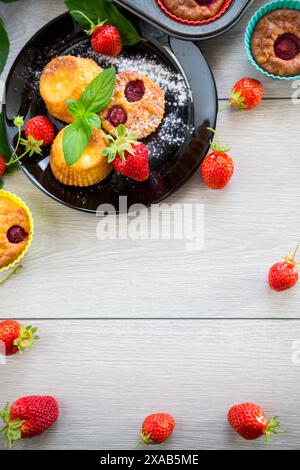 Süße Quark-Muffins mit Erdbeerfüllung, auf einem Teller auf einem Holztisch. Stockfoto