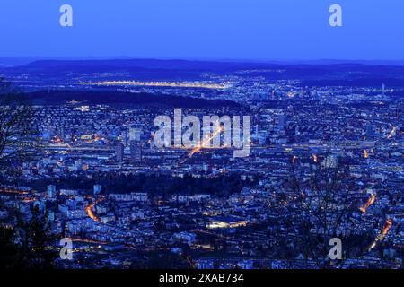 Schweizer Stadt Zürich in blauen Stunden mit dem Flughafen Zürich ganz links über dem Uetliberg Stockfoto