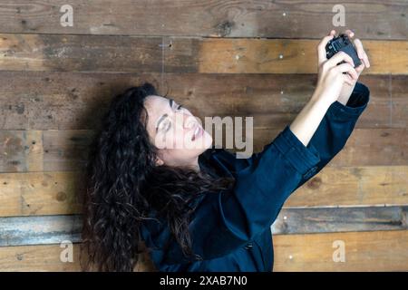 Junge Frau im Trenchcoat, die Selfie mit einer analogen Kamera macht Stockfoto