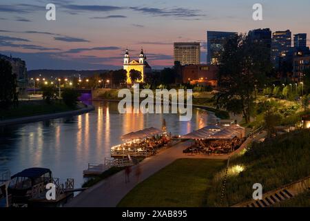 Vilnius bei Sonnenuntergang Panoramablick auf die Stadt mit Fluss Neris, Booten, Café, Kirche und Wolkenkratzern des New Center. Litauen, baltische staaten. Stockfoto