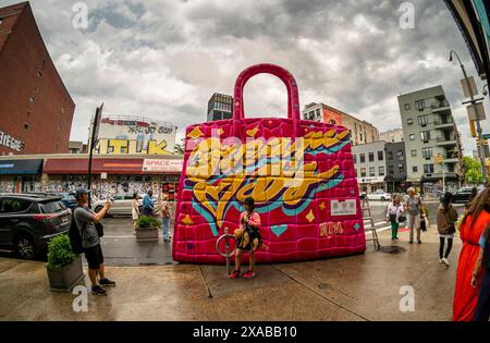 Passanten posieren vor einer riesigen Hermés Birkin Tascheninstallation in Soho in New York am Montag, 27. Mai 2024. Die riesige Tasche ist eine Installation des Künstlers Tom Sachs, der als Teil seiner Kunst Konsumgüter umnutzt oder neue Versionen von ihnen herstellt. (© Richard B. Levine) Stockfoto