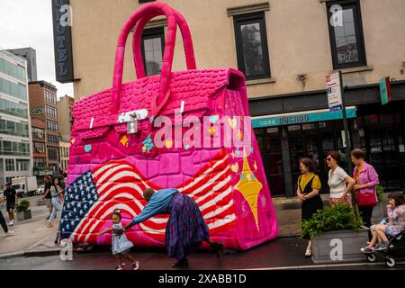 Passanten posieren vor einer riesigen Hermés Birkin Tascheninstallation in Soho in New York am Montag, 27. Mai 2024. Die riesige Tasche ist eine Installation des Künstlers Tom Sachs, der als Teil seiner Kunst Konsumgüter umnutzt oder neue Versionen von ihnen herstellt. (© Richard B. Levine) Stockfoto