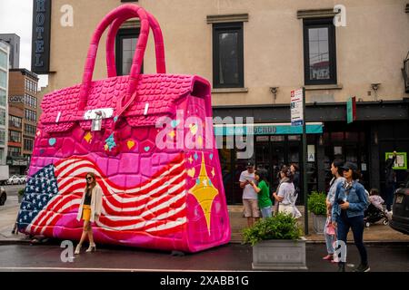 Passanten posieren vor einer riesigen Hermés Birkin Tascheninstallation in Soho in New York am Montag, 27. Mai 2024. Die riesige Tasche ist eine Installation des Künstlers Tom Sachs, der als Teil seiner Kunst Konsumgüter umnutzt oder neue Versionen von ihnen herstellt. (© Richard B. Levine) Stockfoto