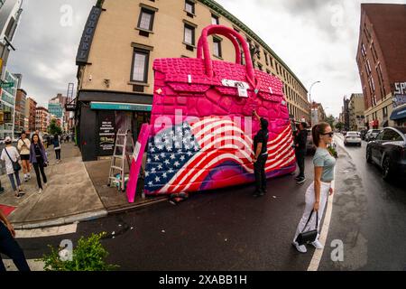 Passanten posieren vor einer riesigen Hermés Birkin Tascheninstallation in Soho in New York am Montag, 27. Mai 2024. Die riesige Tasche ist eine Installation des Künstlers Tom Sachs, der als Teil seiner Kunst Konsumgüter umnutzt oder neue Versionen von ihnen herstellt. (© Richard B. Levine) Stockfoto