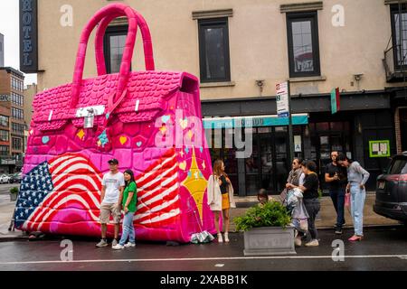 Passanten posieren vor einer riesigen Hermés Birkin Tascheninstallation in Soho in New York am Montag, 27. Mai 2024. Die riesige Tasche ist eine Installation des Künstlers Tom Sachs, der als Teil seiner Kunst Konsumgüter umnutzt oder neue Versionen von ihnen herstellt. (© Richard B. Levine) Stockfoto