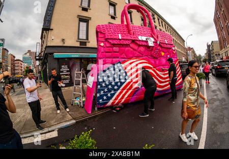 Passanten posieren vor einer riesigen Hermés Birkin Tascheninstallation in Soho in New York am Montag, 27. Mai 2024. Die riesige Tasche ist eine Installation des Künstlers Tom Sachs, der als Teil seiner Kunst Konsumgüter umnutzt oder neue Versionen von ihnen herstellt. (© Richard B. Levine) Stockfoto