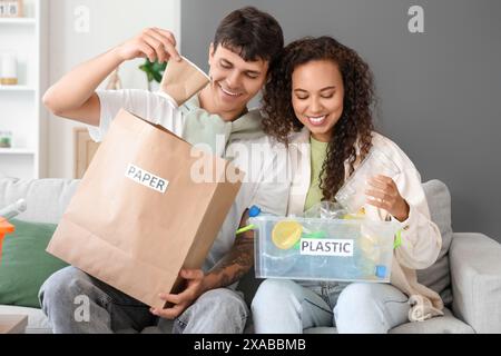 Ein junges Paar, das zu Hause Müll auf dem Sofa sortiert Stockfoto