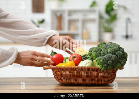 Schwangere Frau, die in der Küche Korb mit unterschiedlichem frischem Gemüse hält Stockfoto