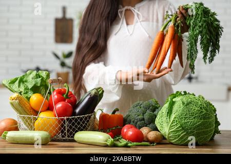 Schwangere Frau mit verschiedenen frischen Gemüsesorten auf hölzernem Küchentisch Stockfoto