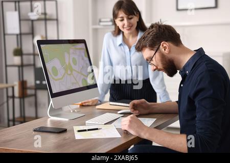 Kartografen arbeiten mit Katasterkarten am Computer am Tisch im Büro Stockfoto