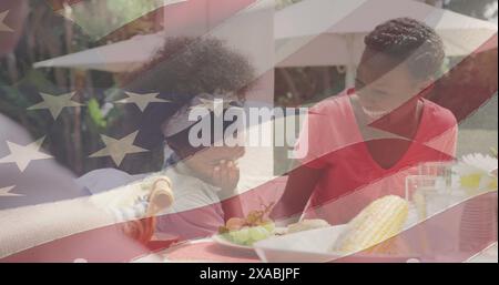 Bild einer amerikanischen Flagge über glücklicher afroamerikanischer Familie, die zu Abend essen und lächelnd Stockfoto