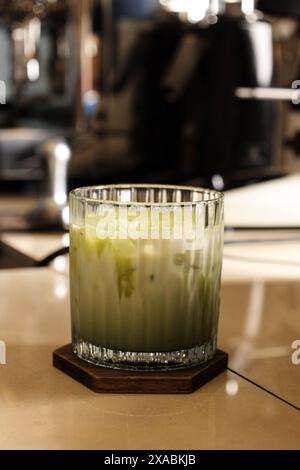 Matcha Green Tea Latte Serve mit kleinem Glas auf Tisch Bar Barista mit Kaffeemaschine Hintergrund Stockfoto