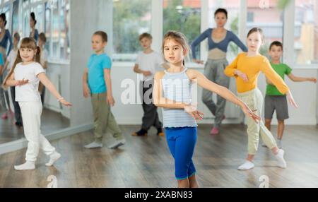 Kinder, die modernen Tanz trainieren, bewegen sich gemeinsam im Studio unter der Leitung des Lehrers Stockfoto