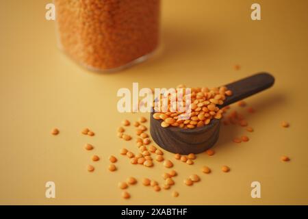 Rote Linsen in einer schwarzen Schaufel auf gelbem Hintergrund erzeugen ein lebendiges und gesundes Bild Stockfoto