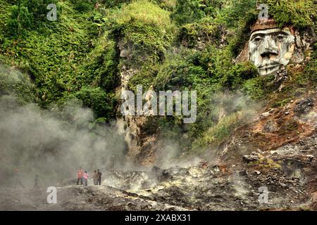 Besucher haben Freizeit auf dem Fumarole-Feld, unter skulpturaler Kunst, die Toar (Ahnenfigur) in Nord-Sulawesi, Indonesien zeigt. Stockfoto