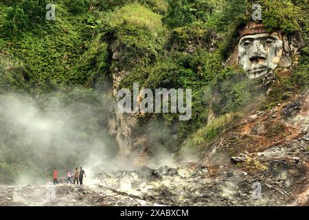 Besucher haben Freizeit auf dem Fumarole-Feld, unter skulpturaler Kunst, die Toar (Ahnenfigur) in Nord-Sulawesi, Indonesien zeigt. Stockfoto