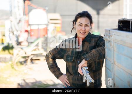 Positive asiatische Arbeiterin, die am Frühlingstag auf dem Hof steht Stockfoto