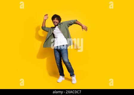 Portraitfoto des jungen lustigen mexikanischen Mannes in Khaki-Hemd tanzende Boogie Woogie auf Hipster-Party isoliert auf gelbem Hintergrund Stockfoto