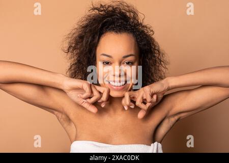 Lächelnde Frau mit lockigem Haar in Einem Handtuch-Massagegesicht Stockfoto