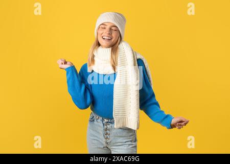 Fröhliche junge Frau, die in Winterkleidung tanzt Stockfoto