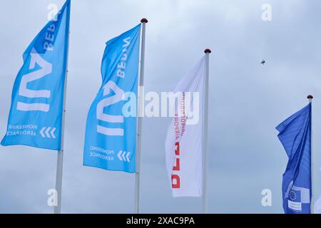 Berlin, Deutschland. Juni 2024. Während die Fahnen der Internationalen Ausstellung für Luft- und Raumfahrt (ILA) fliegen, findet die Flugschau auf dem Gelände des Flughafens Berlin Brandenburg (BER) statt. Die Messe findet vom 5. Bis 9. Juni 2024 unter dem Motto „Pioneering Aerospace“ statt. Annette Riedl/dpa/Alamy Live News Stockfoto