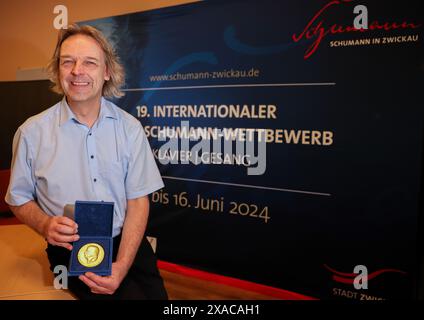 05. Juni 2024, Sachsen, Zwickau: Thomas Synofzik, Direktor des Robert-Schumann-Hauses und Vorsitzender der Jury des Internationalen Robert-Schumann-Wettbewerbs für Klavier und Gesang, steht vor einem Logo der Veranstaltung. In den nächsten zehn Tagen werden 66 junge Pianisten und 79 Sängerinnen und Sänger erwartet, darunter auch einige aus Asien und Amerika. Die Stadt Zwickau, in der der Komponist Robert Schumann geboren wurde, veranstaltet alle vier Jahre den nach ihm benannten Musikwettbewerb. Dieses Jahr findet sie vom 6. Bis 16. Juni zum 19. Mal statt. Die Preise für die besten Virtuosen werden mit bis zu 10.000 Preisen bestückt Stockfoto