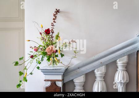 Inneneinrichtung mit Blumenstrauß und Glamelia in Vase auf Holztreppensäule. Feder Stockfoto