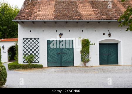 Fotografie eines alten traditionellen alpinen Bauernhauses mit weißen Wänden, rotem Ziegeldach und grünen Holztoren Stockfoto