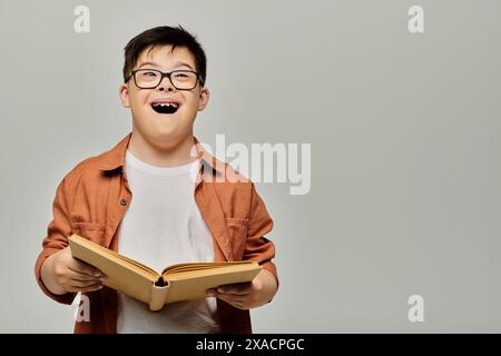 Ein Kind mit Down-Syndrom in Brille liest ein Buch intensiv. Stockfoto