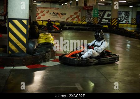 Fahren Sie mit dem Kart Racer um die Kurve während des Rennens auf der Hallenbahn. Kiew - 26. Januar 2024 Stockfoto