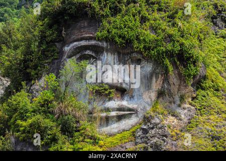 Großes, geschnitztes Gesicht in Bukit Kasih, einem vulkanischen Touristenpark mit Fumarole-Feldern, einem Weltfriedenturm und Gotteshäusern von fünf großen Religionen, Stockfoto