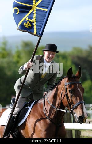 Hawick, Großbritannien. Juni 2024. Ryan Nichol trägt die ungebuschte Flagge "Banner Blue", nachdem er St. Leonards verlassen hat, galoppiert er "Roond the Mair", bevor er vor dem zeremoniellen Beginn des Common Riding in der Stadt Dienst nimmt. Später heute, Donnerstag, den 06. Juni 2024, ist Hawick Common Riding die erste der jährlichen Grenzveranstaltungen. es feiert die Gefangennahme einer englischen Flagge von einer Raidparty im Jahr 1514 durch die Jugend von Hawick in Hornshole und den alten Brauch, auf den Märschen oder Grenzen des gemeinsamen Landes zu reiten. Quelle: Rob Gray/Alamy Live News Stockfoto