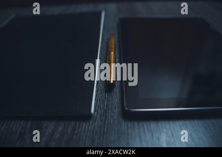 Am Arbeitsplatz. Notizbuch mit Stift und Tablet auf einem Holztisch. Strenger STYLE. Hochwertige Fotos Stockfoto
