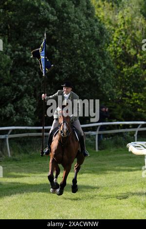 Hawick, Großbritannien. Juni 2024. Ryan Nichol trägt die ungebuschte Flagge "Banner Blue", nachdem er St. Leonards verlassen hat, galoppiert er "Roond the Mair", bevor er vor dem zeremoniellen Beginn des Common Riding in der Stadt Dienst nimmt. Später heute, Donnerstag, den 06. Juni 2024, ist Hawick Common Riding die erste der jährlichen Grenzveranstaltungen. es feiert die Gefangennahme einer englischen Flagge von einer Raidparty im Jahr 1514 durch die Jugend von Hawick in Hornshole und den alten Brauch, auf den Märschen oder Grenzen des gemeinsamen Landes zu reiten. Quelle: Rob Gray/Alamy Live News Stockfoto