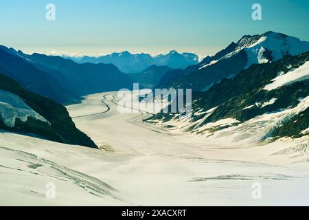 Eine verschneite Bergkette mit einem Fluss, der durch sie fließt. Der Fluss ist gefroren und die Berge sind mit Schnee bedeckt. Die Szene ist friedlich und ruhig Stockfoto