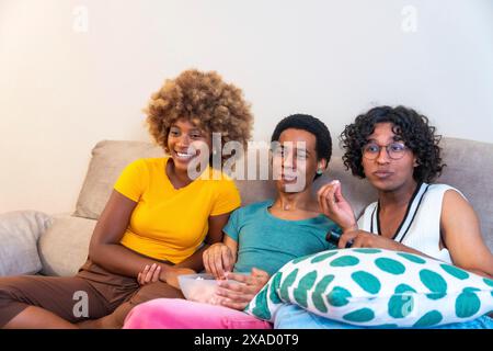 Multiethnische Freunde schauen sich Filme an und essen Popcorn auf dem Sofa zu Hause Stockfoto