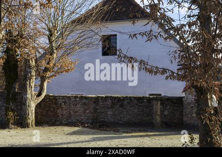 Fotografie eines alten traditionellen alpinen Bauernhauses mit rotem Ziegeldach und Fenster am sonnigen Wintertag Stockfoto