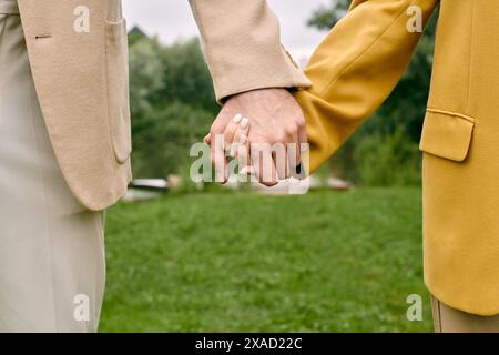 Eine Nahaufnahme von zwei Personen, ein wunderschönes Paar, die Hände zärtlich in einem grünen Park halten und Liebe und Verbundenheit zeigen. Stockfoto
